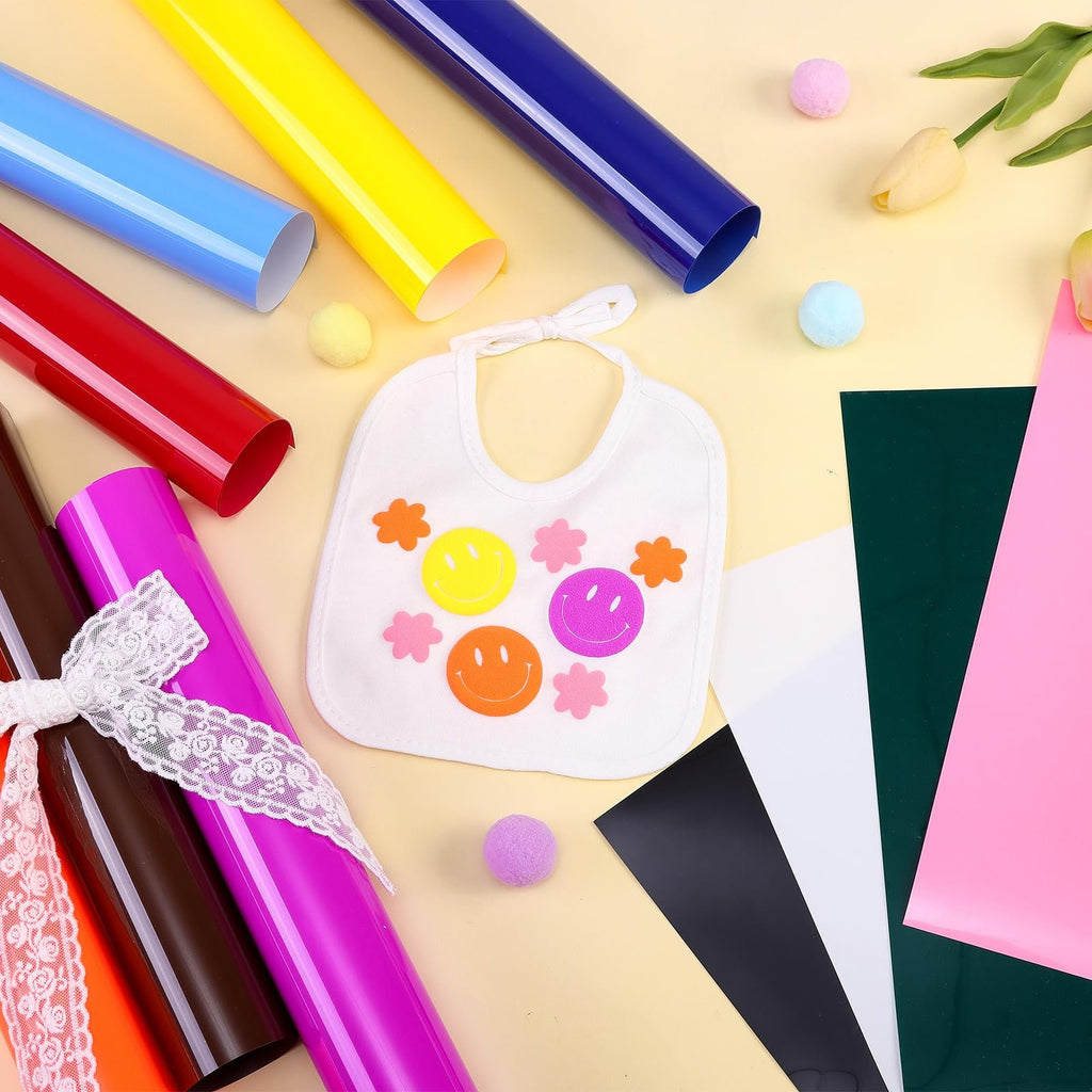 Assorted rolls of heat transfer vinyl and a white bib with smiley faces and flowers