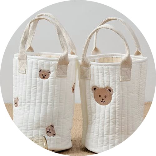 Two quilted white storage bags with embroidered teddy bear faces and handles, displayed side-by-side.