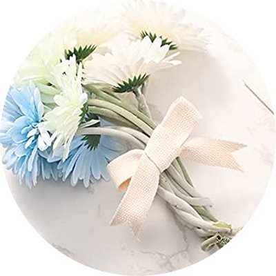 Close-up of a bouquet of artificial gerbera daisies with blue and white petals, tied with a cream ribbon.