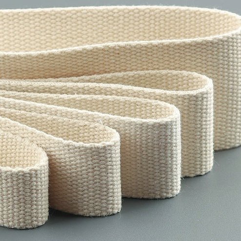 Close-up of natural cotton webbing roll with multiple layers creating depth and texture.
