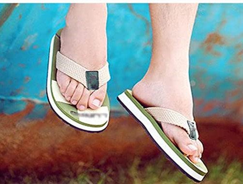 Close-up of a person wearing green and white flip-flops with beige straps.