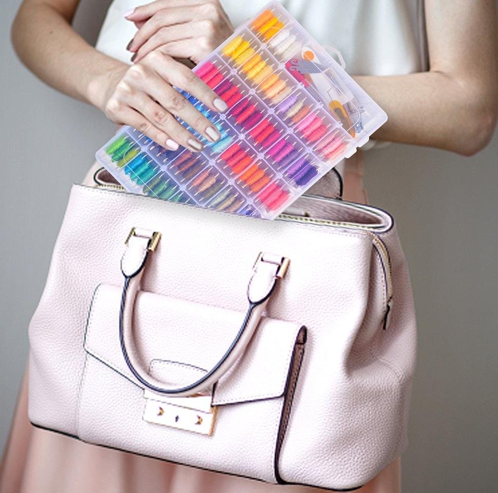 Person holding a clear organizer box filled with colorful embroidery floss over a light pink handbag