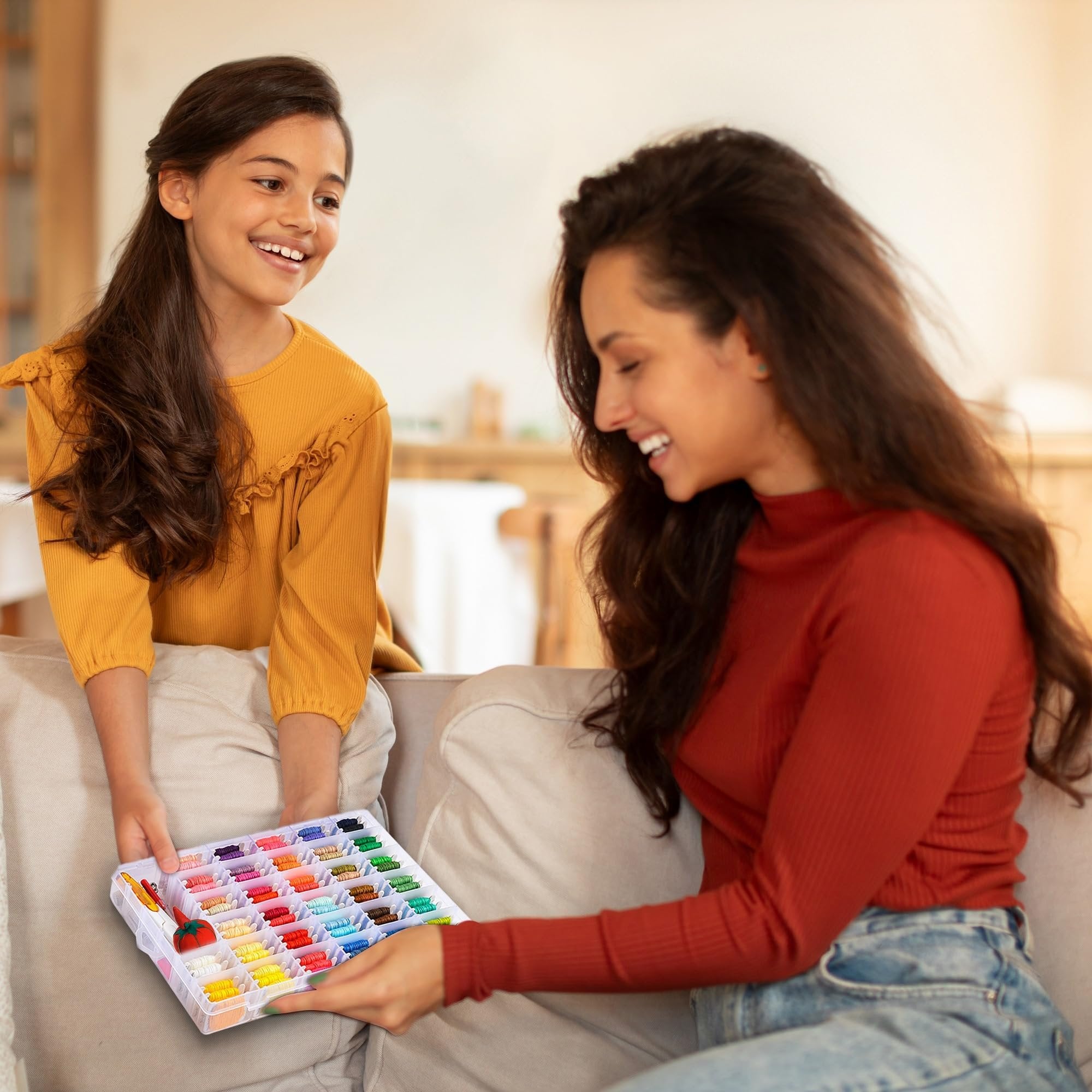 Mother and daughter smiling while holding a clear organizer box filled with colorful embroidery floss.