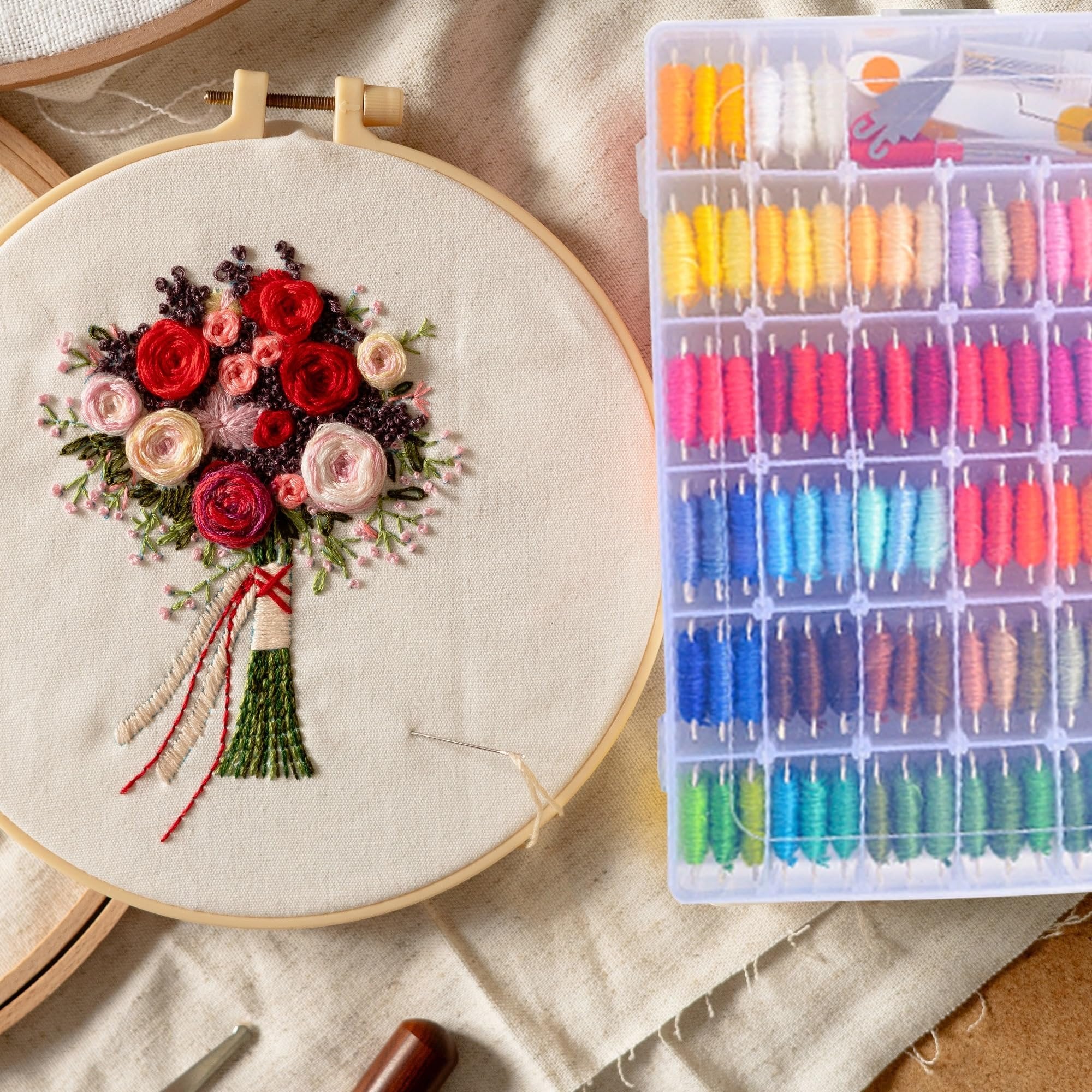 Embroidery hoop with floral design and organizer box filled with colorful embroidery floss