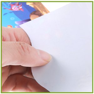 Hand peeling back a white backing sheet from a colorful graphic design.