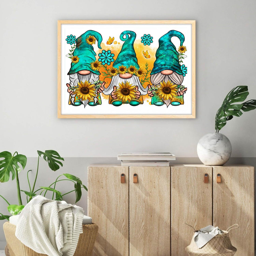 Three gnomes holding sunflowers in a framed artwork on a wall above a wooden cabinet.