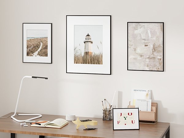 Three framed pictures and a desk with a lamp, notebook, and decorative items.