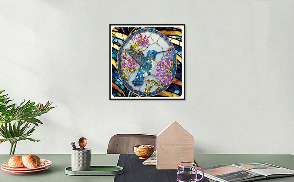 Diamond painting kit featuring a blue hummingbird surrounded by purple flowers in an oval frame, displayed on a wall.