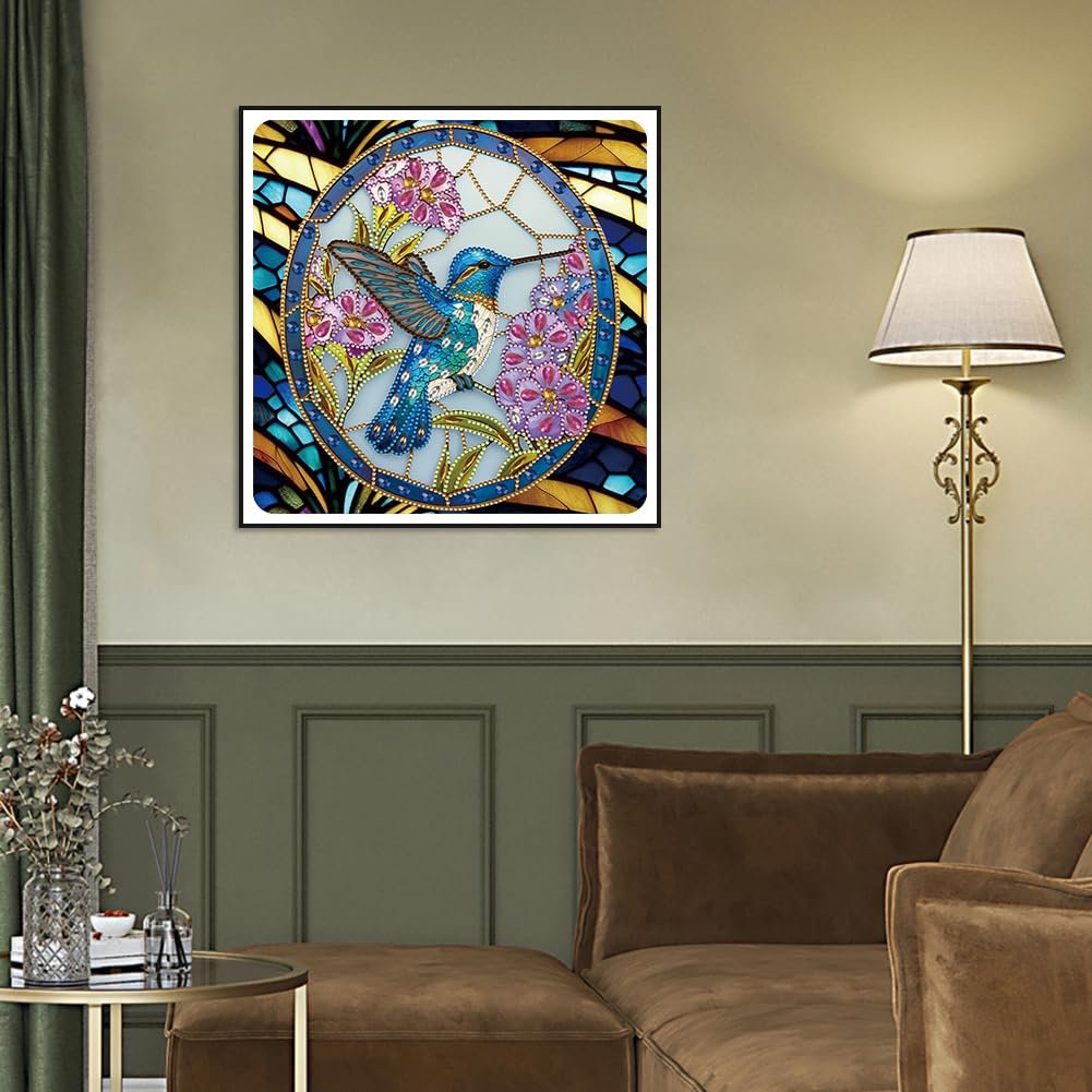 Diamond painting kit featuring a blue hummingbird surrounded by pink flowers in an oval frame, displayed on a wall.