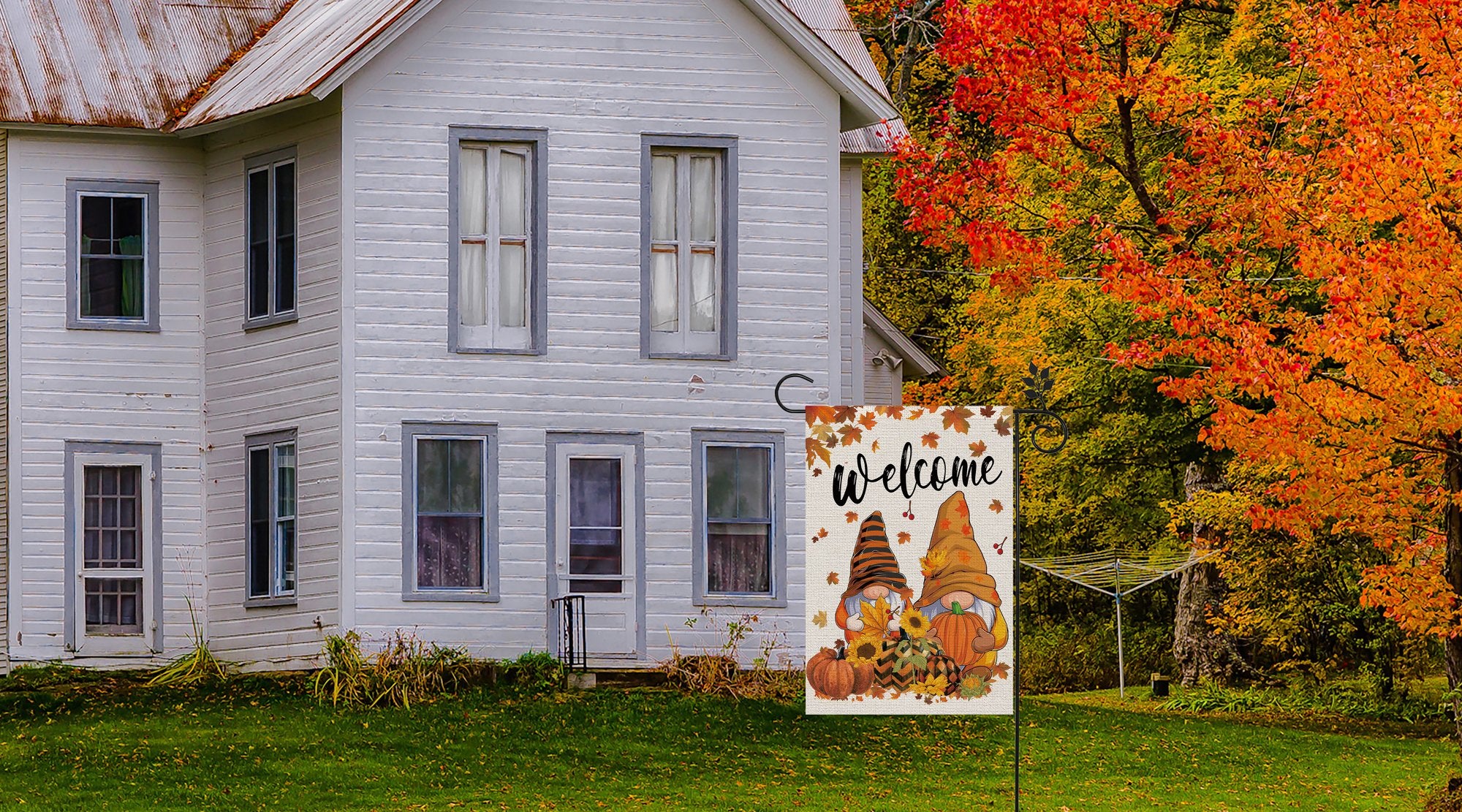 Fall garden flag with two gnomes, pumpkins, and sunflowers, displaying the word 'welcome' against a backdrop of a white house and autumn trees.
