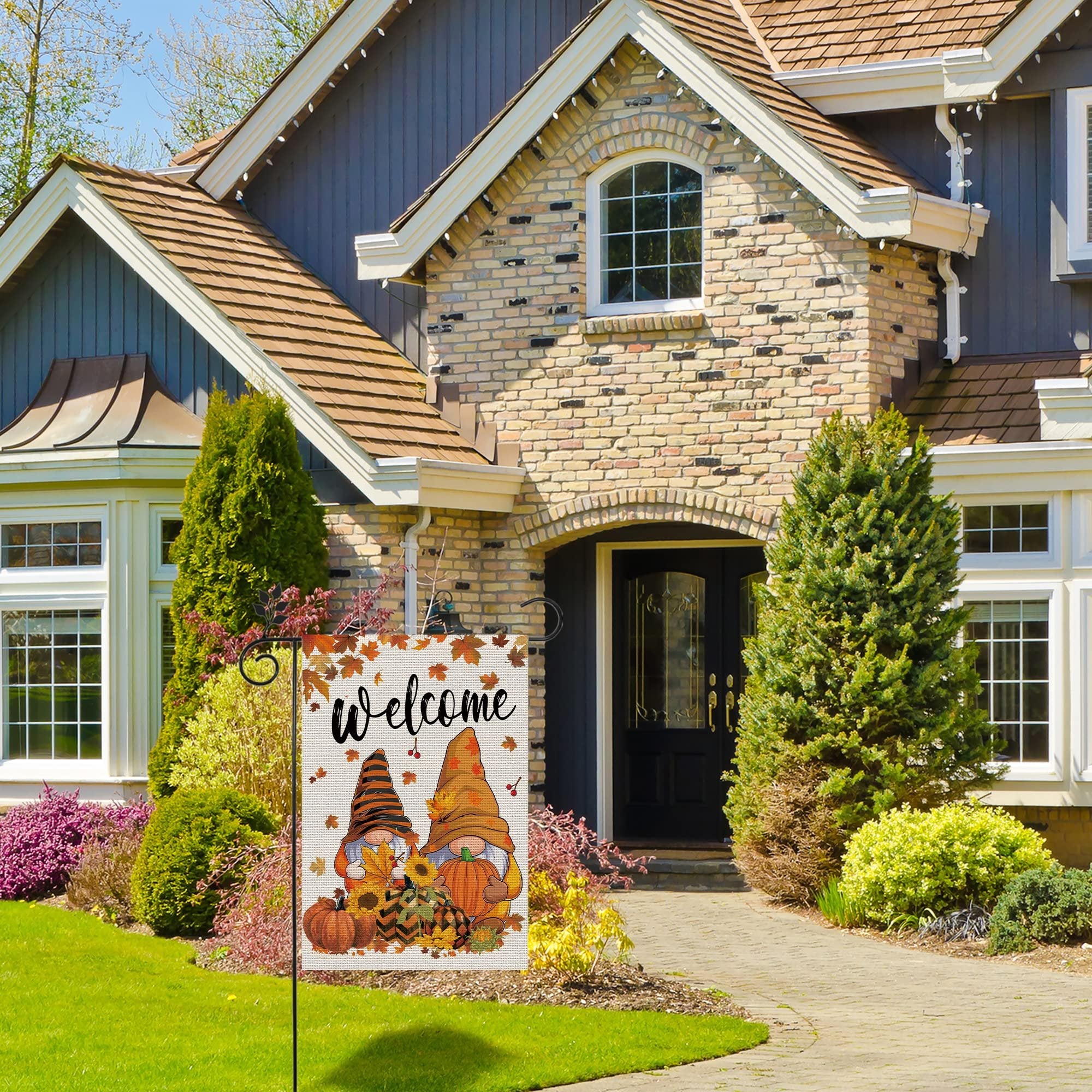 Fall garden flag with two gnomes, pumpkins, and sunflowers, displaying the word 'welcome' in front of a house.