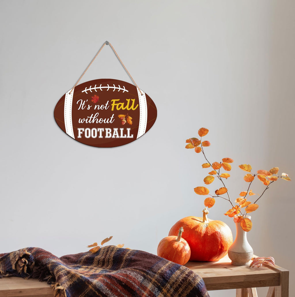 Oval wooden football-shaped fall hanging sign with text 'It's not Fall without FOOTBALL', displayed on a wall.