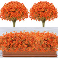 Two bunches of artificial orange flowers with green leaves and one planter filled with artificial orange flowers