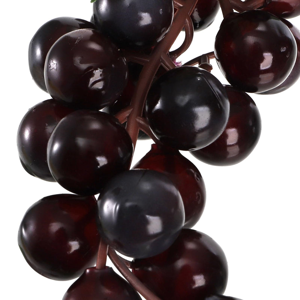 Close-up of dark artificial grapes on a brown stem against a white background.