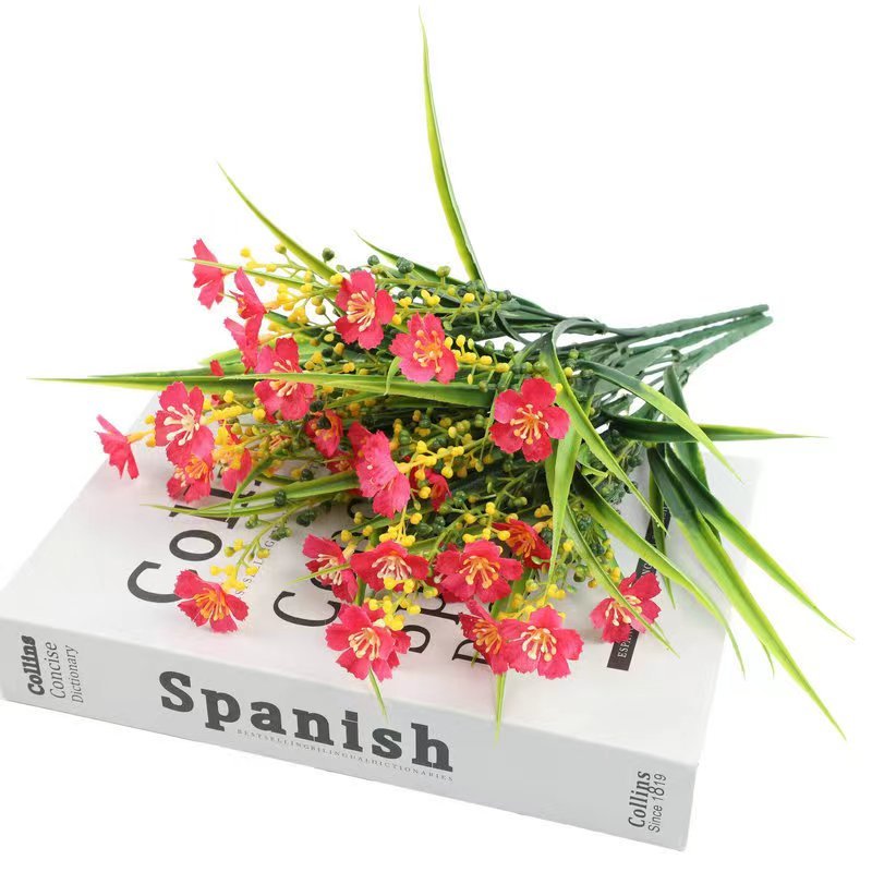 Artificial daisy flowers with red blossoms and yellow accents arranged on a Spanish dictionary.
