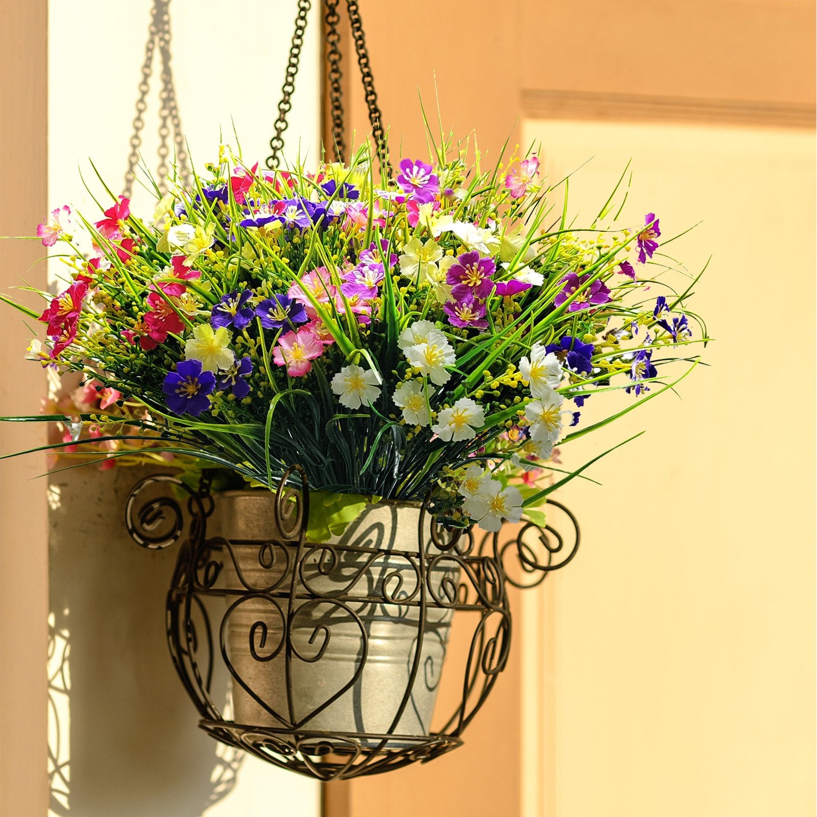 Hanging basket filled with artificial daisies in mixed colors and green foliage, suspended by a chain.