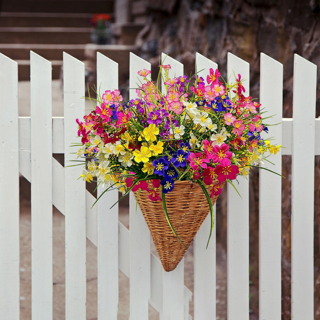 Artificial daisy flowers in a woven basket hanging on a white picket fence