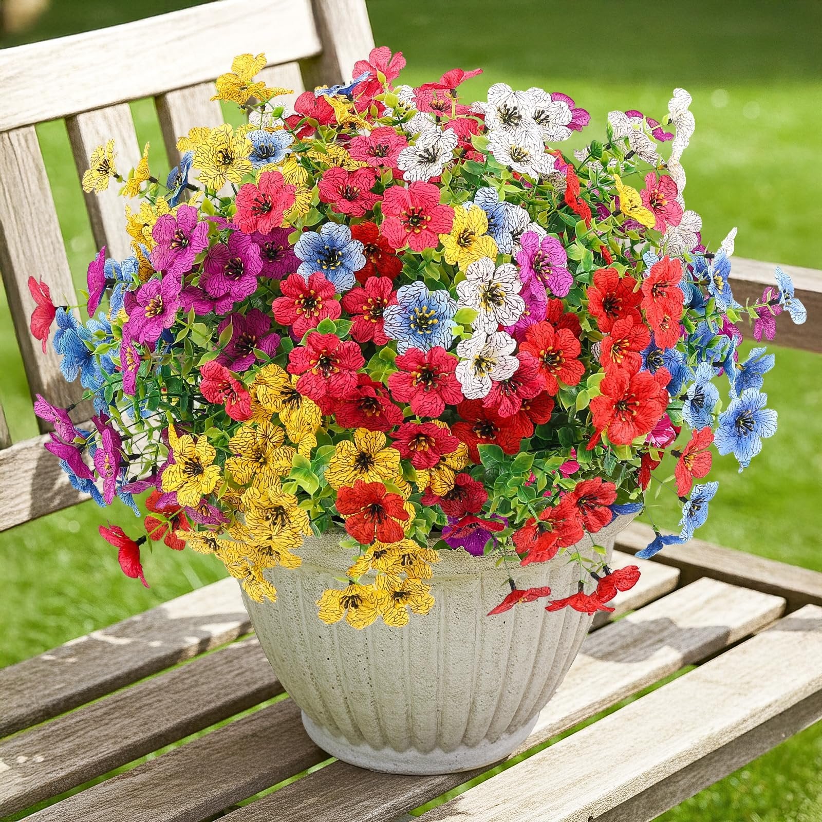 Multicolor artificial daisy flowers in a pot on a wooden bench, featuring red, yellow, blue, pink, and white blooms.