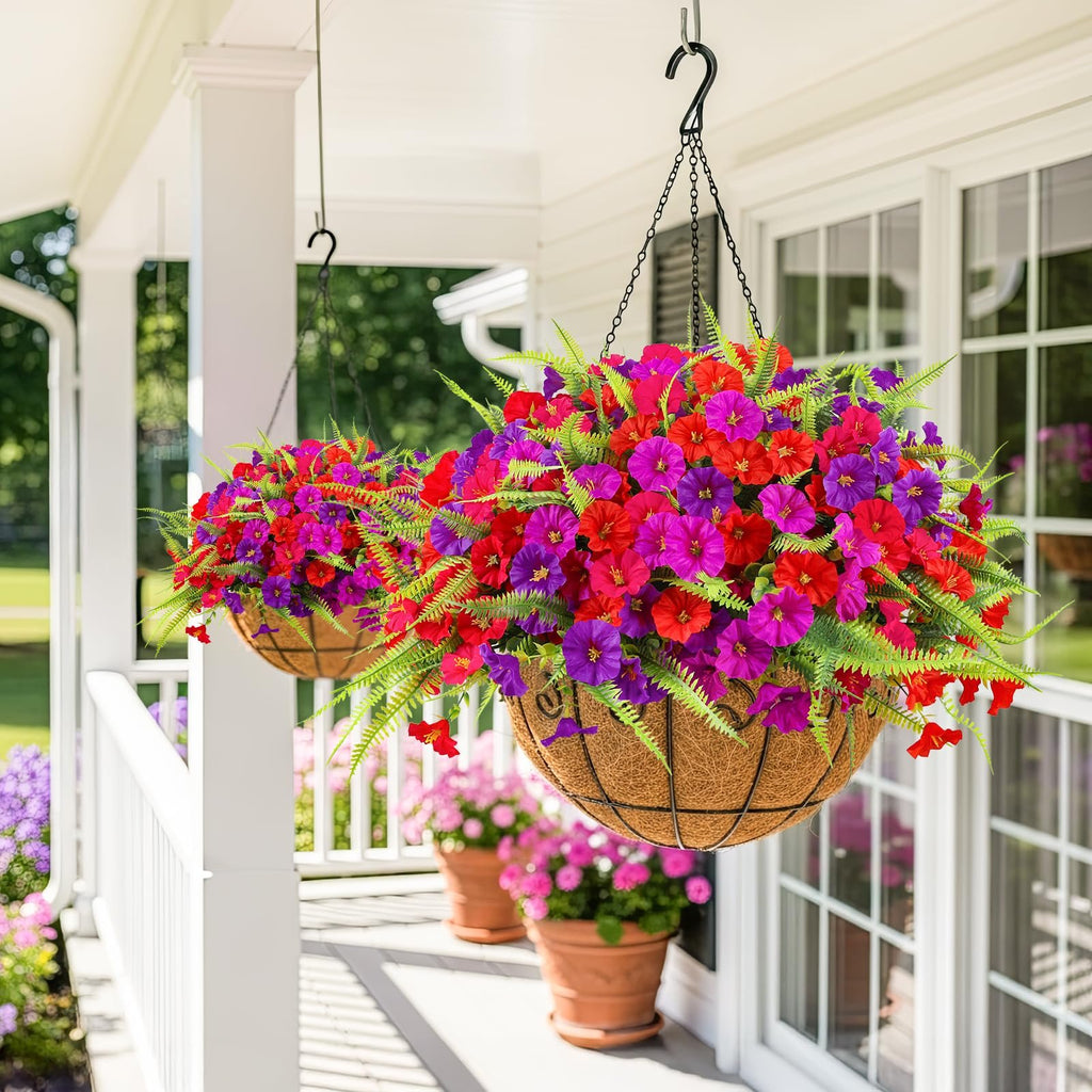 Two hanging baskets filled with artificial red and purple petunias and ferns on a porch.