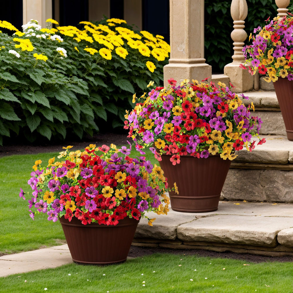 Two brown planters filled with colorful artificial daisy flowers and eucalyptus leaves on a stone patio and lawn.