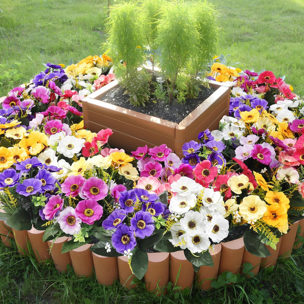 Circular arrangement of mixed color artificial daisy silk flowers around a planter with green foliage.