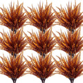 Twelve bundles of artificial fall fern and mum plants with brown and orange foliage, displayed in a grid pattern on a white background.