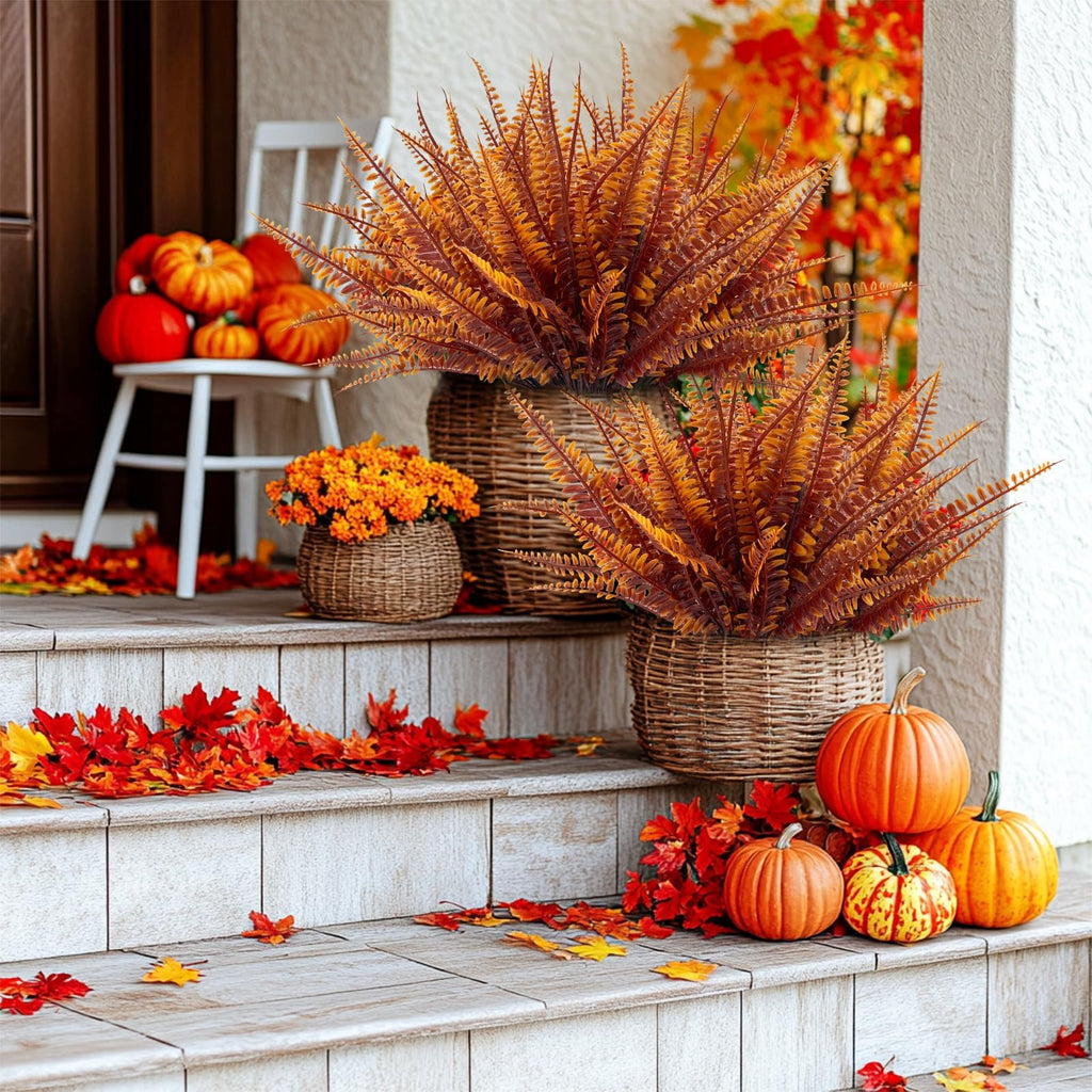 Autumn porch decor with artificial ferns in baskets, pumpkins, and scattered fall leaves on steps.