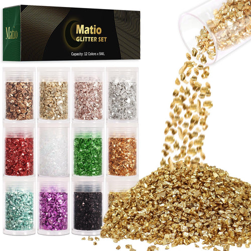 Twelve small jars of crushed glass glitter in various colors, with a pile of gold glitter spilling from a jar.