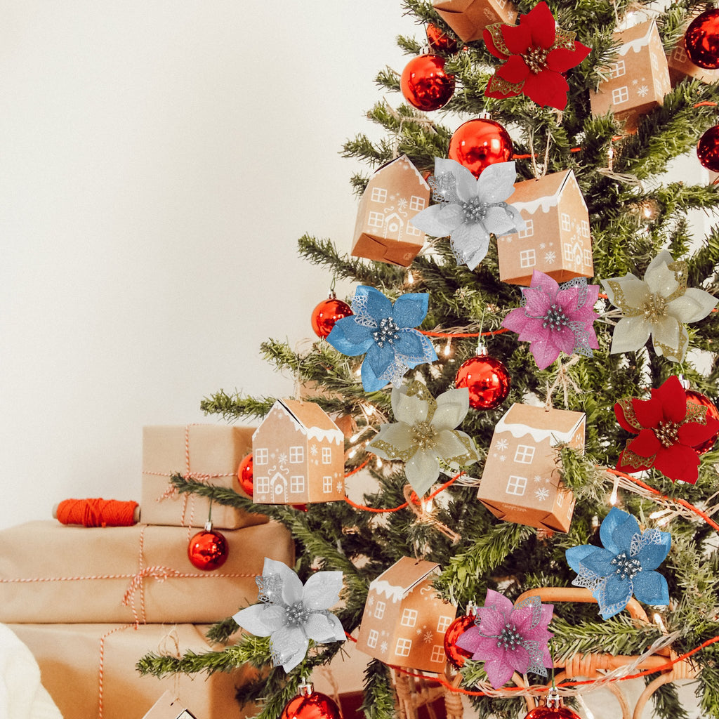 Christmas tree decorated with artificial poinsettia flowers, red ornaments, and gingerbread house ornaments.