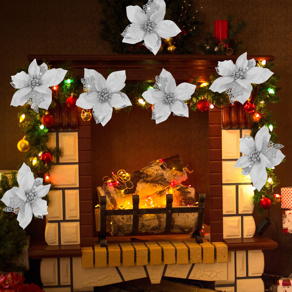 Artificial white poinsettia flowers with glitter and metal clips decorating a Christmas fireplace mantel with garland and lights