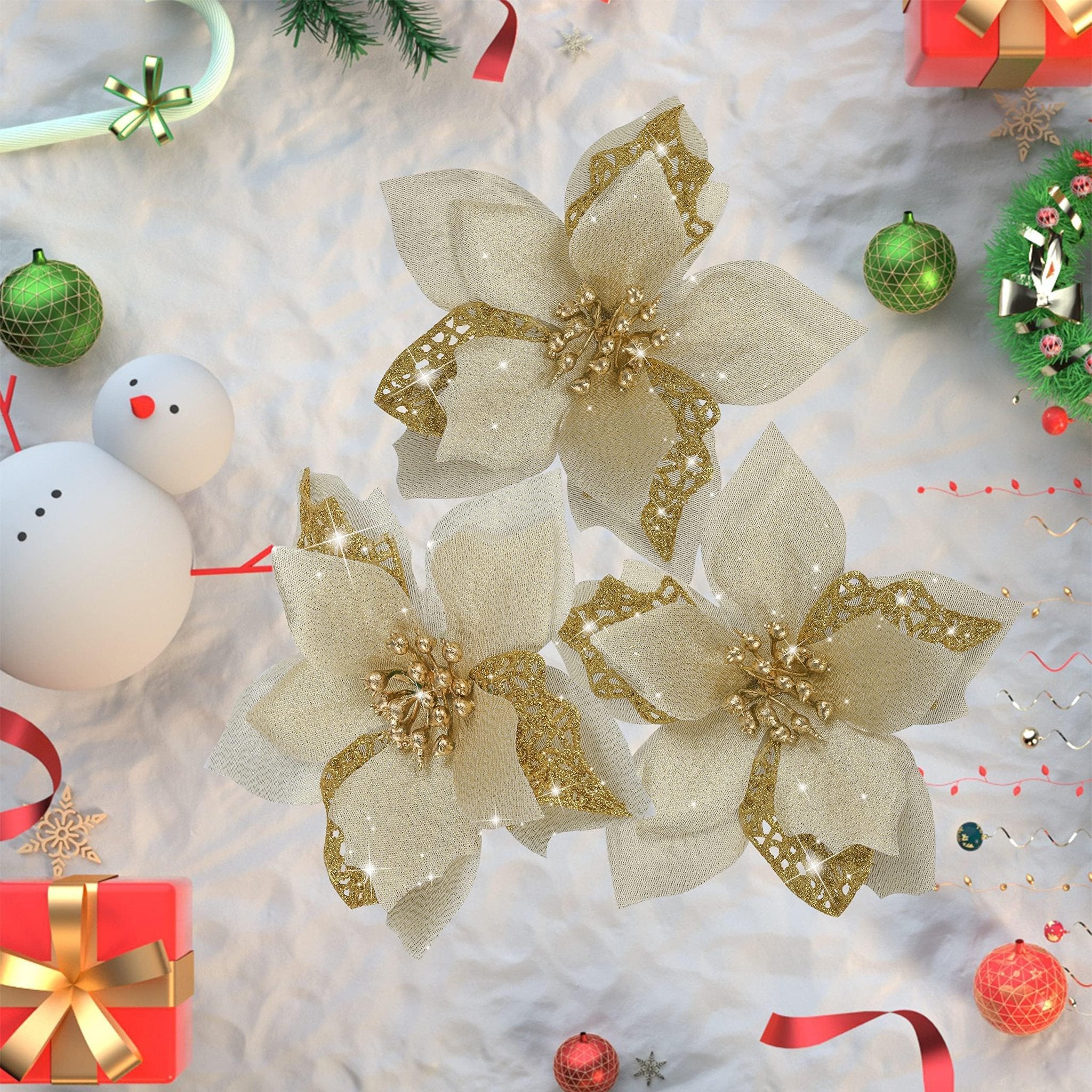 Three gold glitter artificial poinsettia flowers with metal clips arranged on a white textured surface with Christmas decorations.