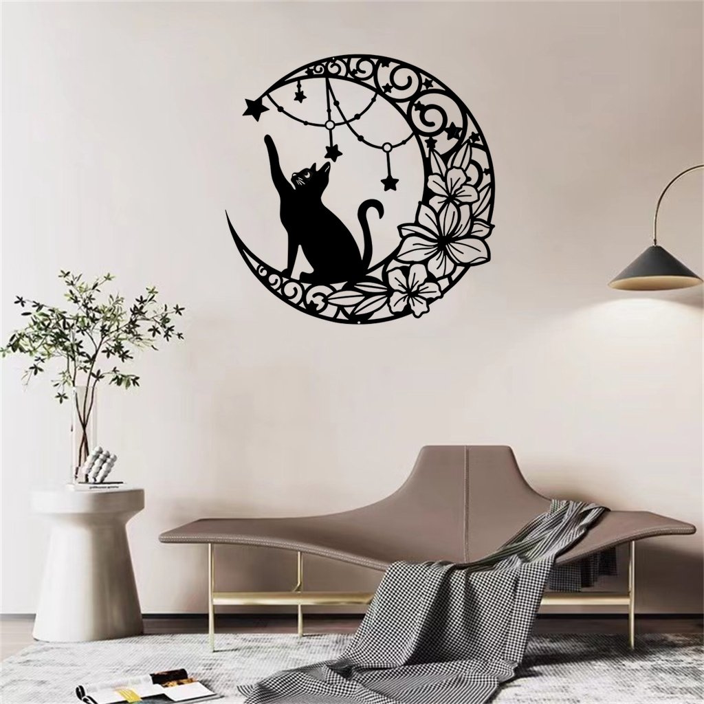 Black metal moon cat wall decor with stars and flowers hanging on a white wall above a sofa.