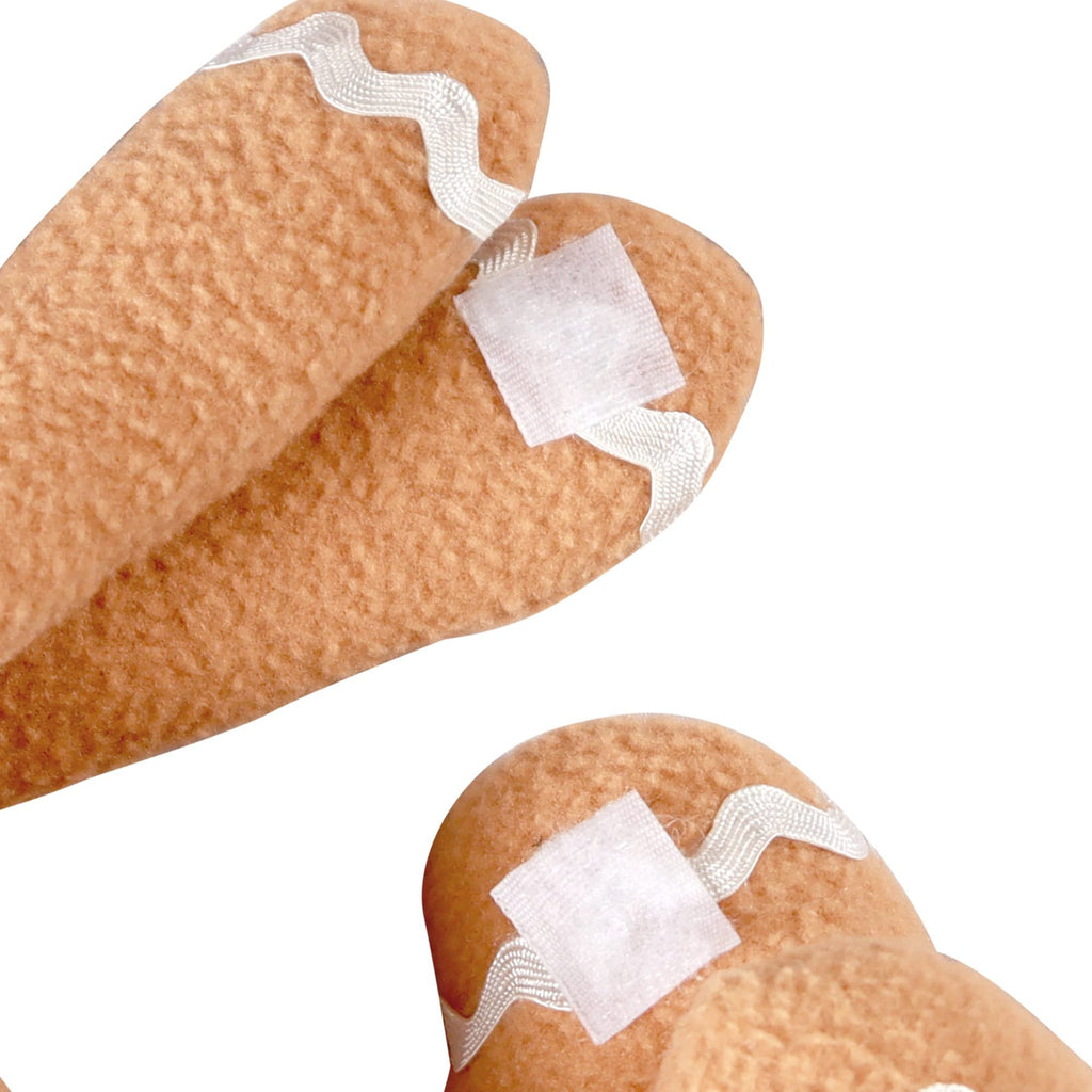 Close-up of gingerbread man plush toy hands with white bandages and decorative white trim.