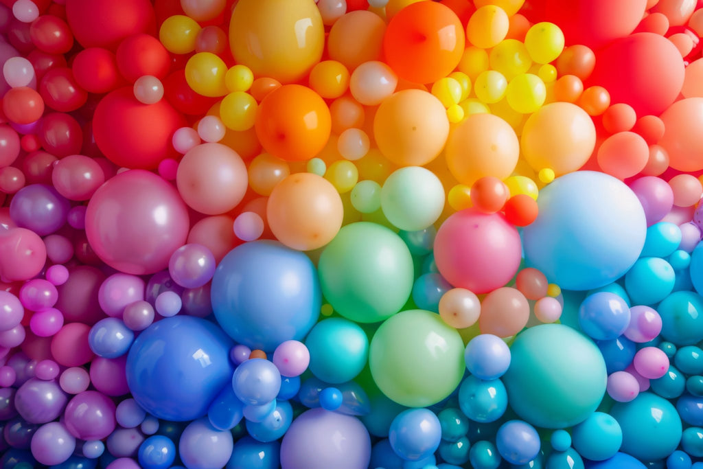 A vibrant, close-up view of a large collection of pearlized latex balloons in various sizes and colors, arranged in a dense, overlapping pattern.