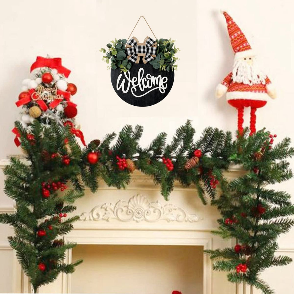 Round wooden welcome sign with eucalyptus wreath and plaid bow, displayed with Christmas decorations.