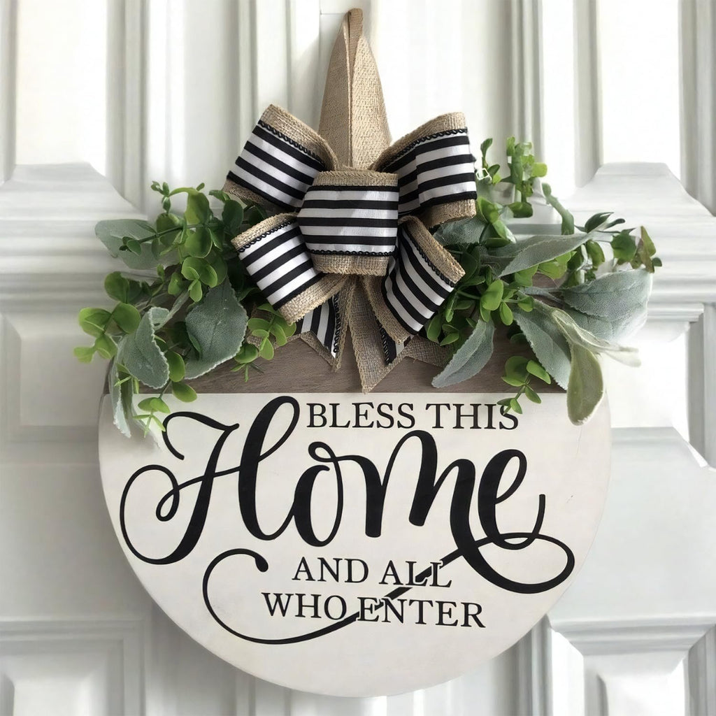 Round wooden welcome sign with greenery and black and white striped bow, reads 'Bless This Home And All Who Enter'