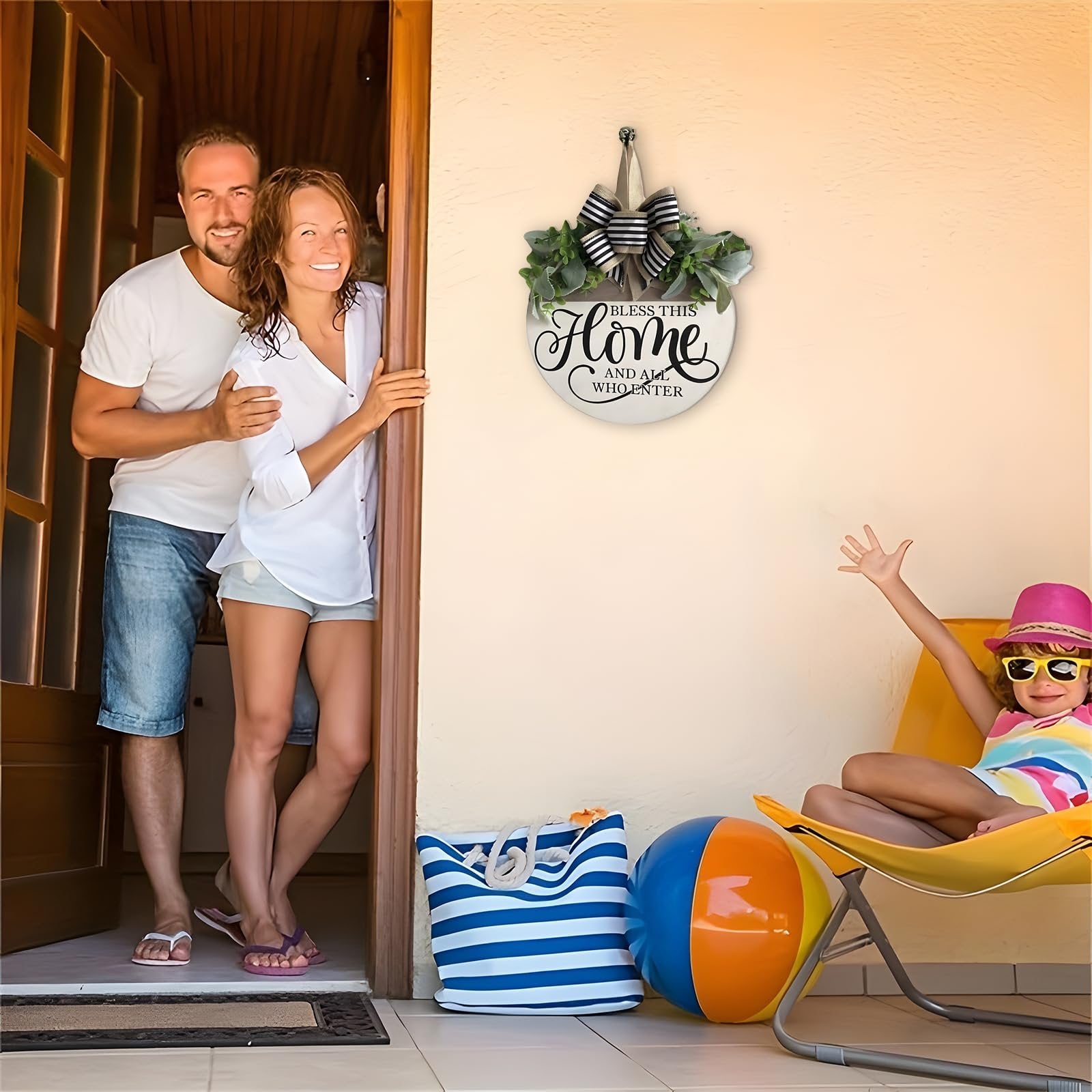 Couple at doorway and child on chair with beach ball and bag, round welcome sign hanging on wall