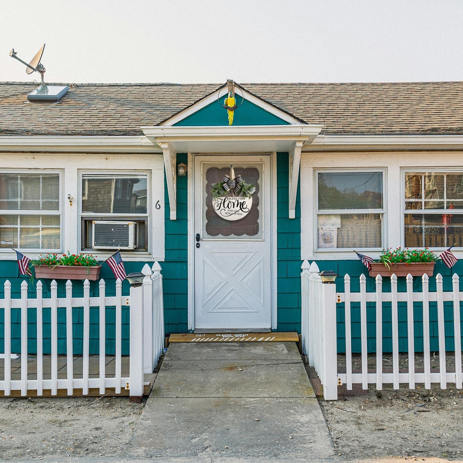 Front door of a house decorated with a round wooden welcome wreath with greenery and a black and white striped bow.