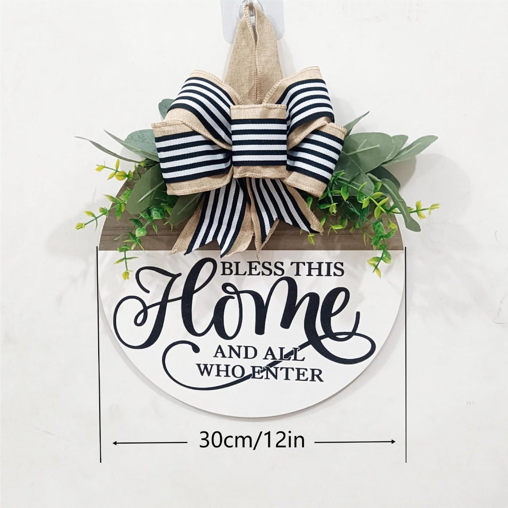 Round wooden welcome sign with a burlap bow and greenery, reads 'Bless this Home and all who enter'.