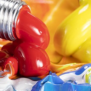 Close-up of red, yellow, and blue oil paints being squeezed from tubes onto a palette.