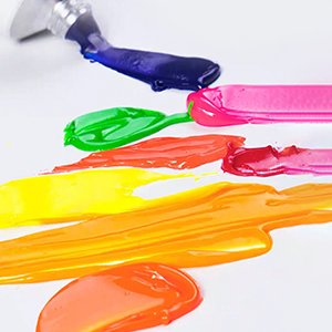 Neon oil paint colors squeezed from a tube onto a white surface, showing streaks of blue, green, pink, orange, yellow, and red.