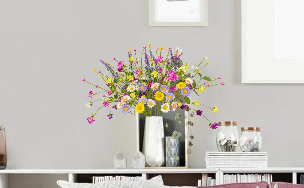Arrangement of artificial spring flowers with daisies, lavender, and pip berries in a white vase on a shelf.