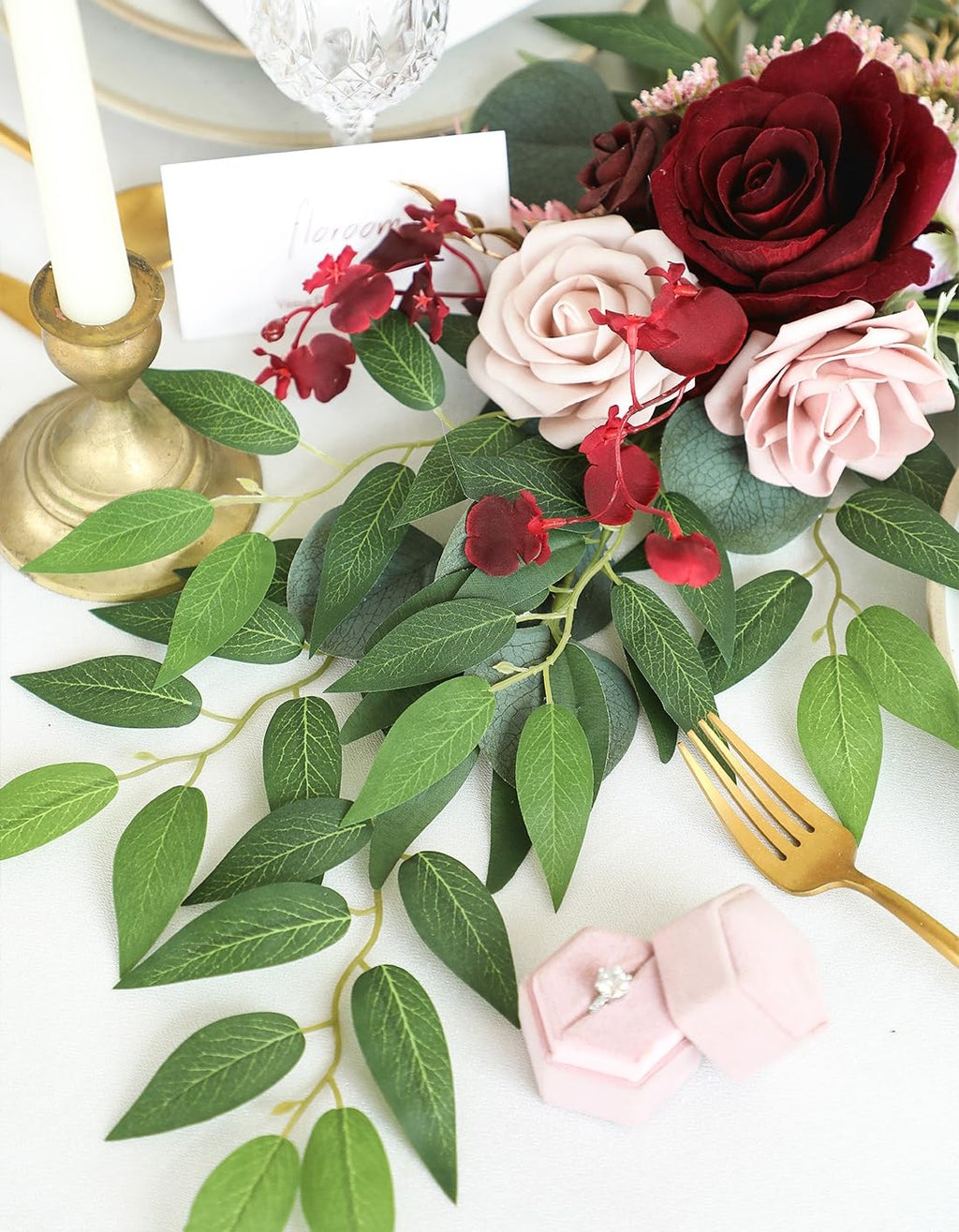 Artificial Italian Ruscus greenery stems with faux silk leaves arranged with roses on a table setting.