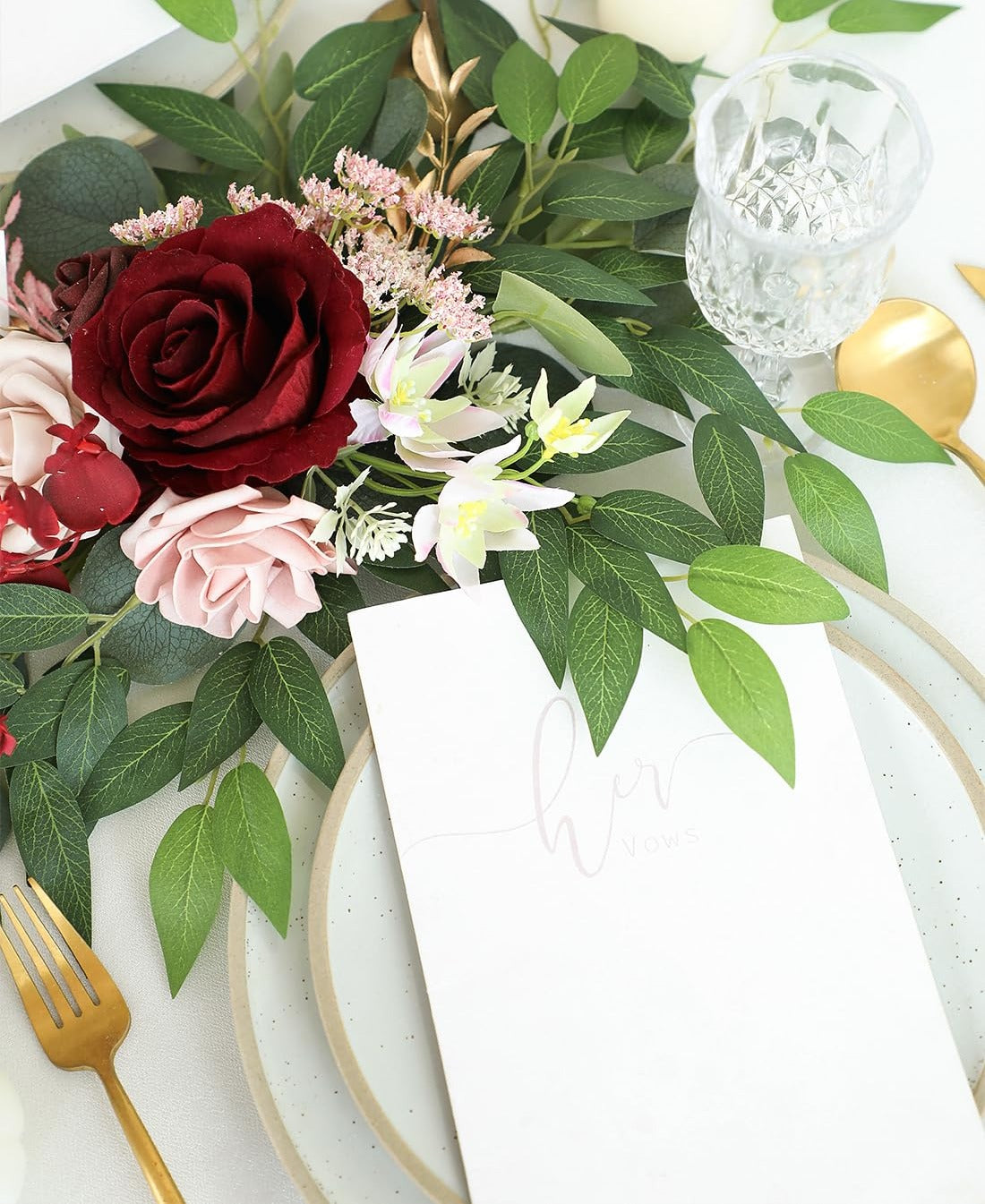 Artificial Italian Ruscus greenery stems with red and pink roses arranged on a table setting with a menu card.