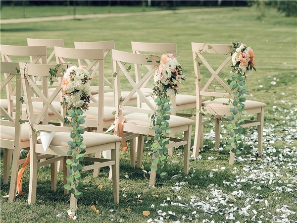 Artificial eucalyptus garland draped on wedding ceremony chairs with floral arrangements
