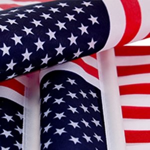 Close-up of multiple US flags rolled together, showing stars and stripes pattern.