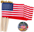 Pack of 12 American stick flags with wooden poles and gold spear tops, shown fanned out with a circular inset of flags decorating a picnic table.