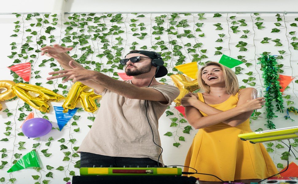 Couple dancing at a party with artificial ivy vines and balloons decorating the wall