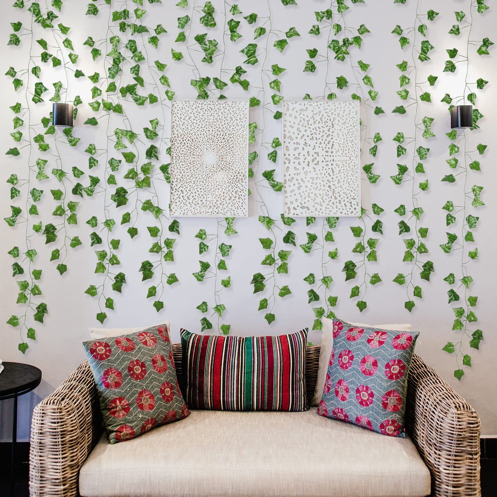Artificial ivy vines draped on a wall behind a sofa with decorative pillows and wall art