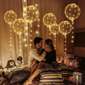 Couple embracing surrounded by clear LED light-up balloons and string lights